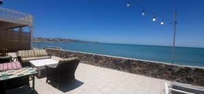 An outdoor seating area with stone walls, a view of the sea, and string lights. - Multi Unit Beachfront EScape (Puerto Peñasco)