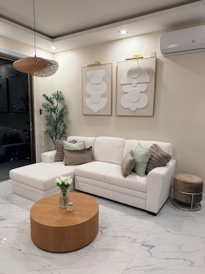 A modern living room with a sofa, a round coffee table, and decorative wall art.