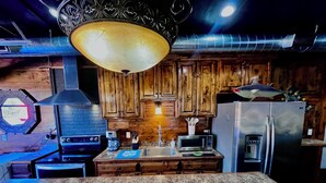 Una cocina con armarios de madera, un refrigerador de acero inoxidable, un microondas y una estufa a gas.