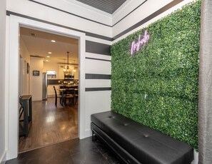 Ein Empfangsbereich mit grüner Wand, einer Neonreklame, einer Bank und Blick in den Speisesaal.