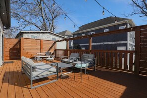 Eine Holzterrasse mit Gartenmöbeln, einer Pergola und Blick auf Nachbarhäuser.