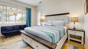 Un dormitorio con una cama, mesitas de noche, un sofá y un ventilador de techo.