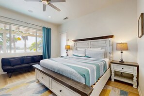 Ein Schlafzimmer mit Bett, Nachttischen, einer Schlafcouch und einem Deckenventilator.