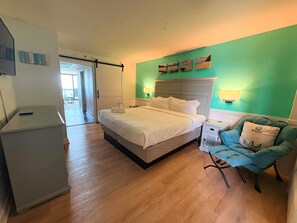 Ett hotellrum med en säng, en stol, ett nattduksbord och utsikt över omgivningen.