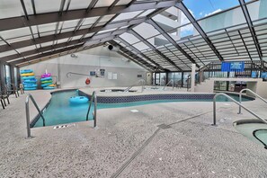 Ett inomhuspoolområde med ett glastak, en bubbelpool och uppblåsbara badringar.