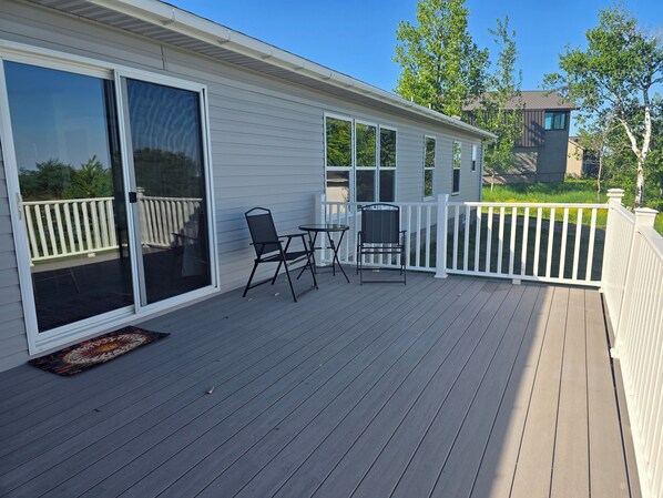 Eine Terrasse mit Glastür, zwei Stühlen und einem kleinen Tisch.