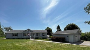 Ein zweistöckiges Haus mit Veranda, Garage und gepflegtem Rasen.