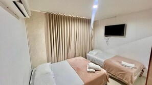 A hotel room with two beds, a TV mounted on the wall, and an air conditioning unit. - Vilma Luxury Rentals marina del rey laguito building (Cartagena de Indias)