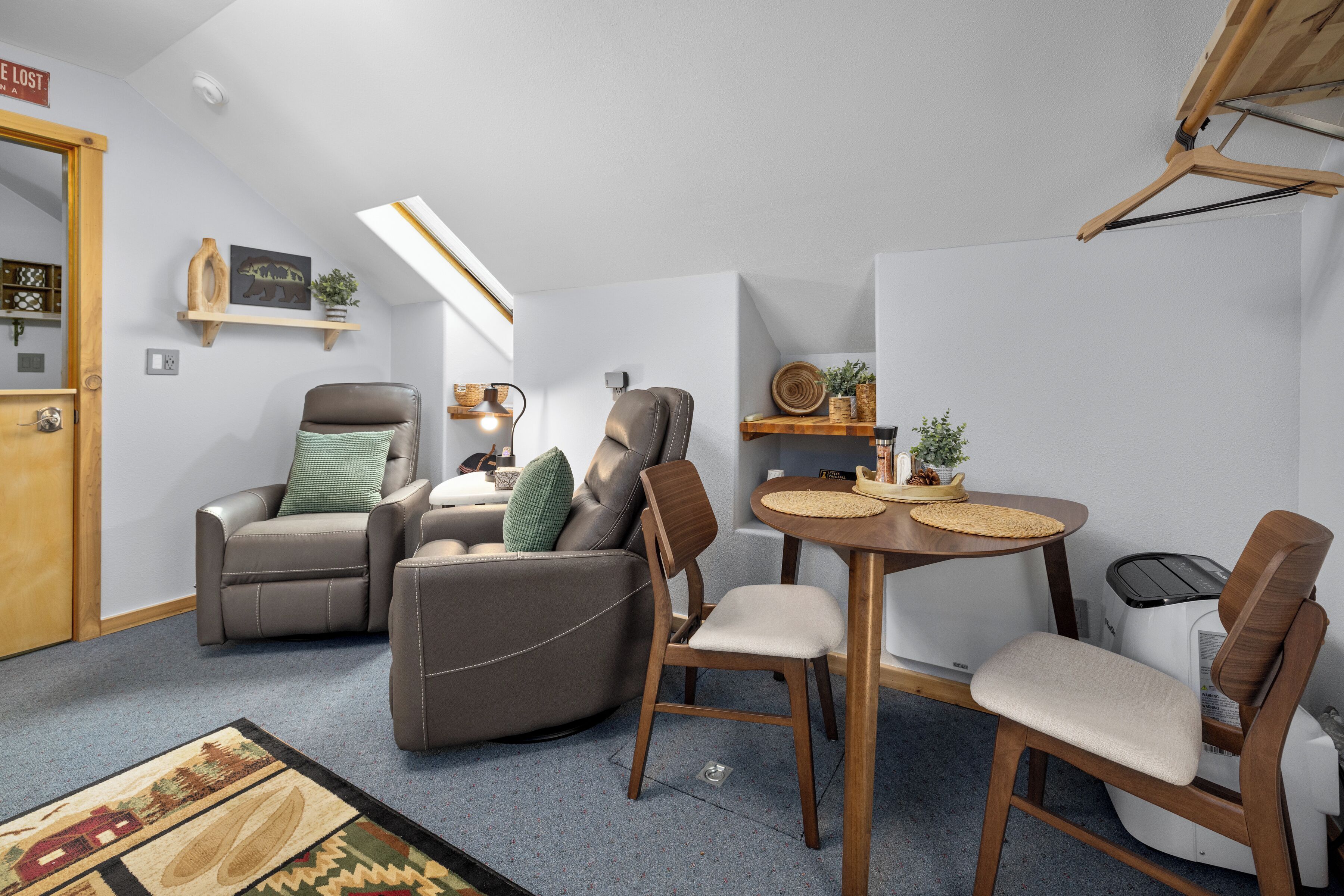 A compact living space with a sofa, chairs, a dining table, and a small kitchen area.
