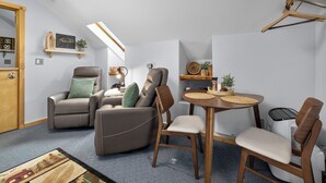 Ett kompakt vardagsrum med en soffa, stolar, ett matbord och ett litet köksutrymme.
