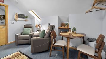 A compact living space with a sofa, chairs, a dining table, and a small kitchen area.