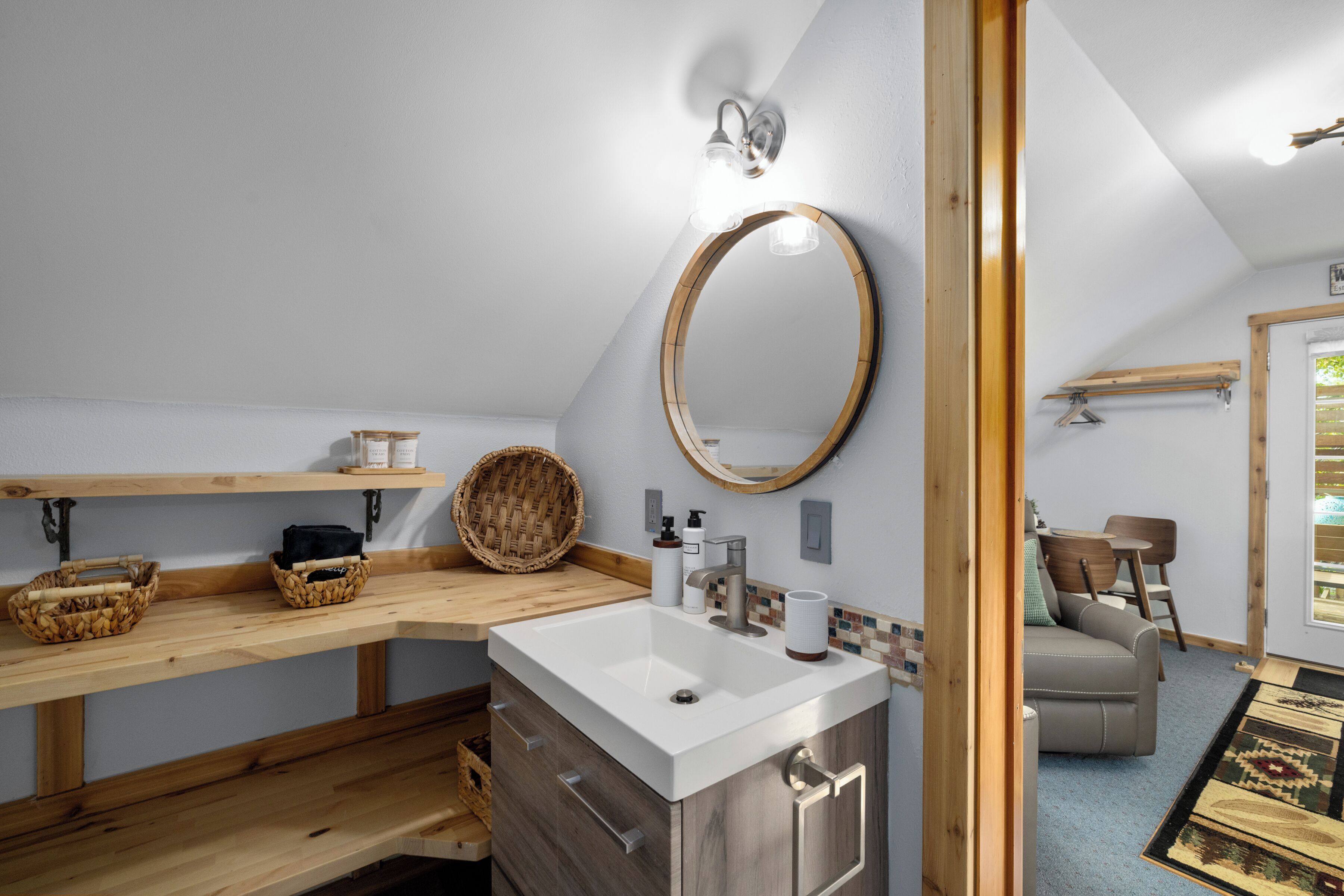A bathroom with a wooden vanity, a large mirror, and a white sink.