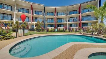 A multi-story hotel with a swimming pool, balconies, and a red heart-shaped decoration.
