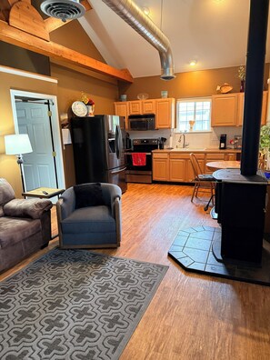 A modern kitchen with wooden cabinets, a black refrigerator, a microwave, and a stove.