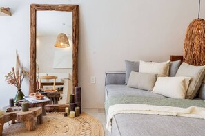 Ein Schlafzimmer mit einem großen Spiegel, einem Bett mit vielen Kissen, einem gewebten Teppich und einem rustikalen Holztisch mit Kerzen.