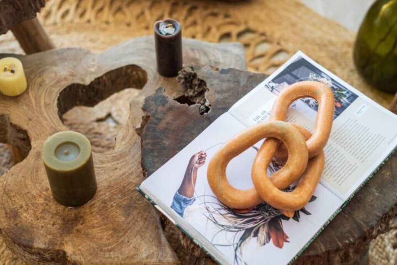 A wooden table with a pretzel, a candle, and a book.