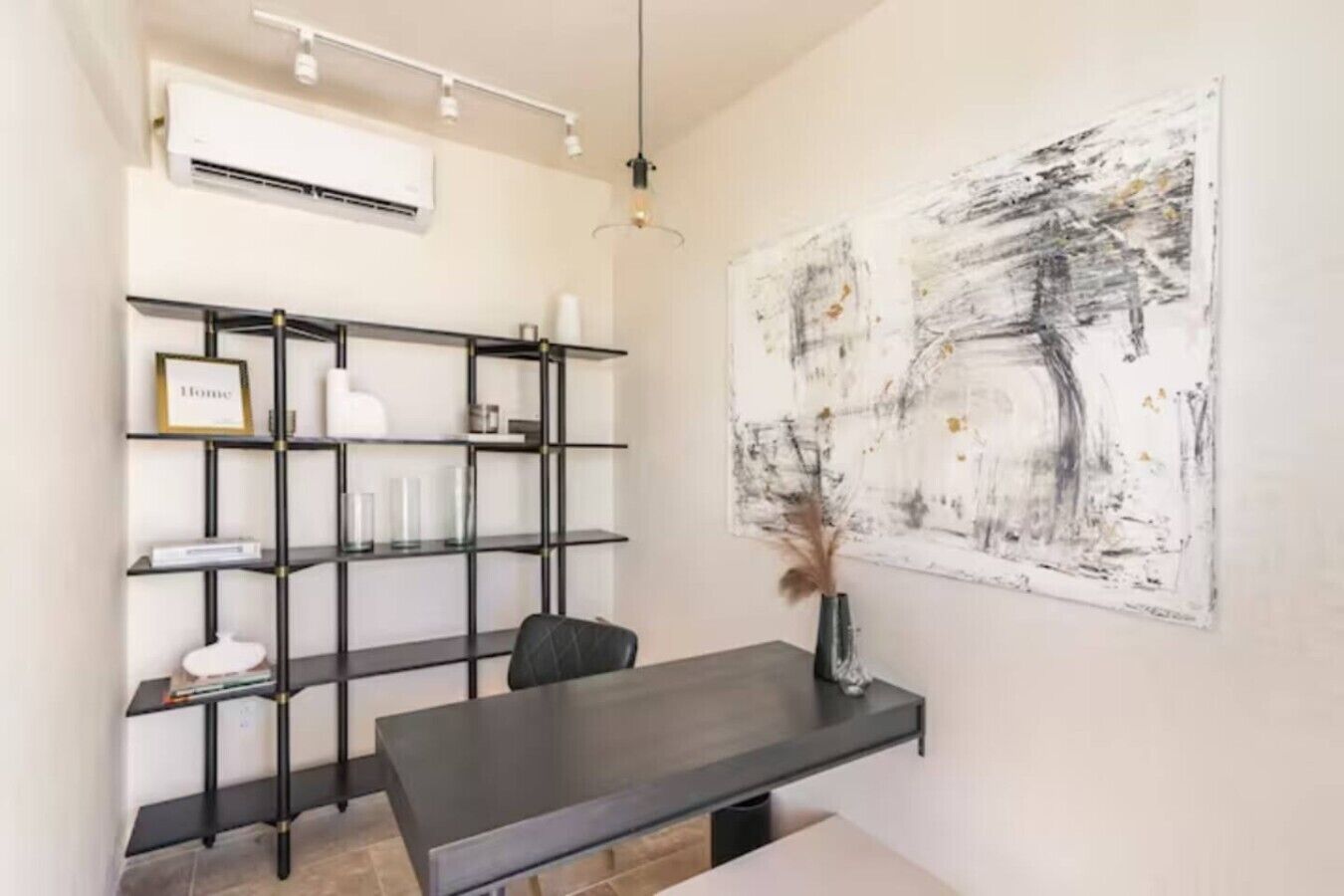 Un intérieur moderne avec une table en bois foncé, une étagère en métal noir et un grand tableau abstrait accroché au mur.