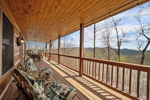 Eine Holzterrasse mit Geländer, Korbmöbeln und einem Tisch.