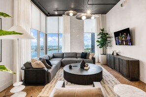 Ein modernes Wohnzimmer mit einer Eckcouch, einem runden Couchtisch und einem großen Fenster mit Blick auf die Stadt.