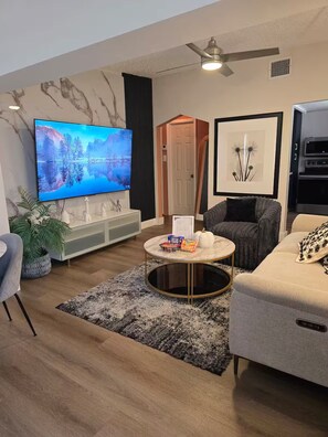 Un salon moderne avec un téléviseur à écran plat, un canapé, une table basse et une cheminée.
