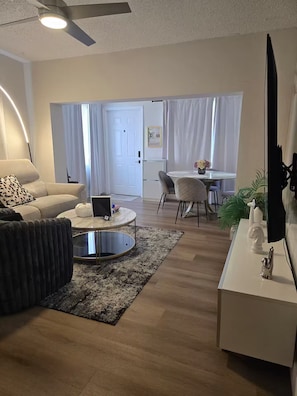 A modern living room with a sofa, coffee table, and dining area. - Your Miami Home • Free Parking (Miami)