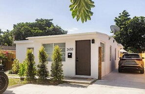 A small, single-story building with a white exterior, a dark brown door, and the number 3450 on the door. - Your Miami Home • Free Parking (Miami)
