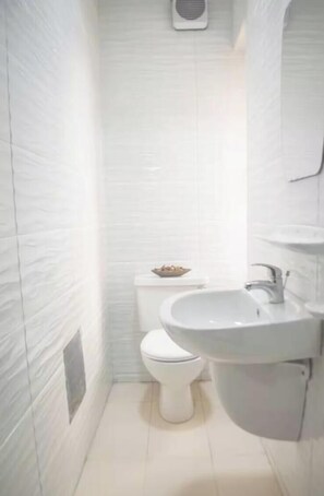 A small, white bathroom with a toilet, a sink, and a mirror. - Two-bed apt, ensuite rooms & close to amenities (Ikeja)