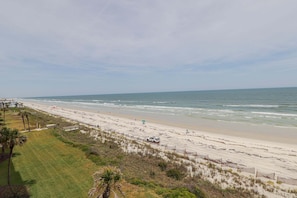 Ein Strand mit sandigem Ufer, einem Zaun und einem geparkten Fahrzeug.