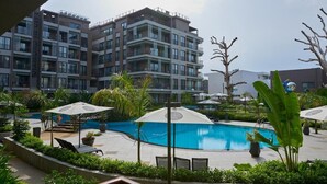 Un hotel moderno con piscina, area salotto esterna e verdeggiante vegetazione.