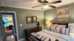 Ein Schlafzimmer mit einem Holzbett, einem Deckenventilator und einem Bild an der Wand.
