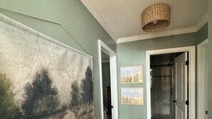 Ein Flur mit Holzdielenboden, einem großen Landschaftsbild und einer Tür zu einem Badezimmer.