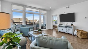 Una sala de estar moderna con un sofá, sillones, una mesita de centro y un televisor.
