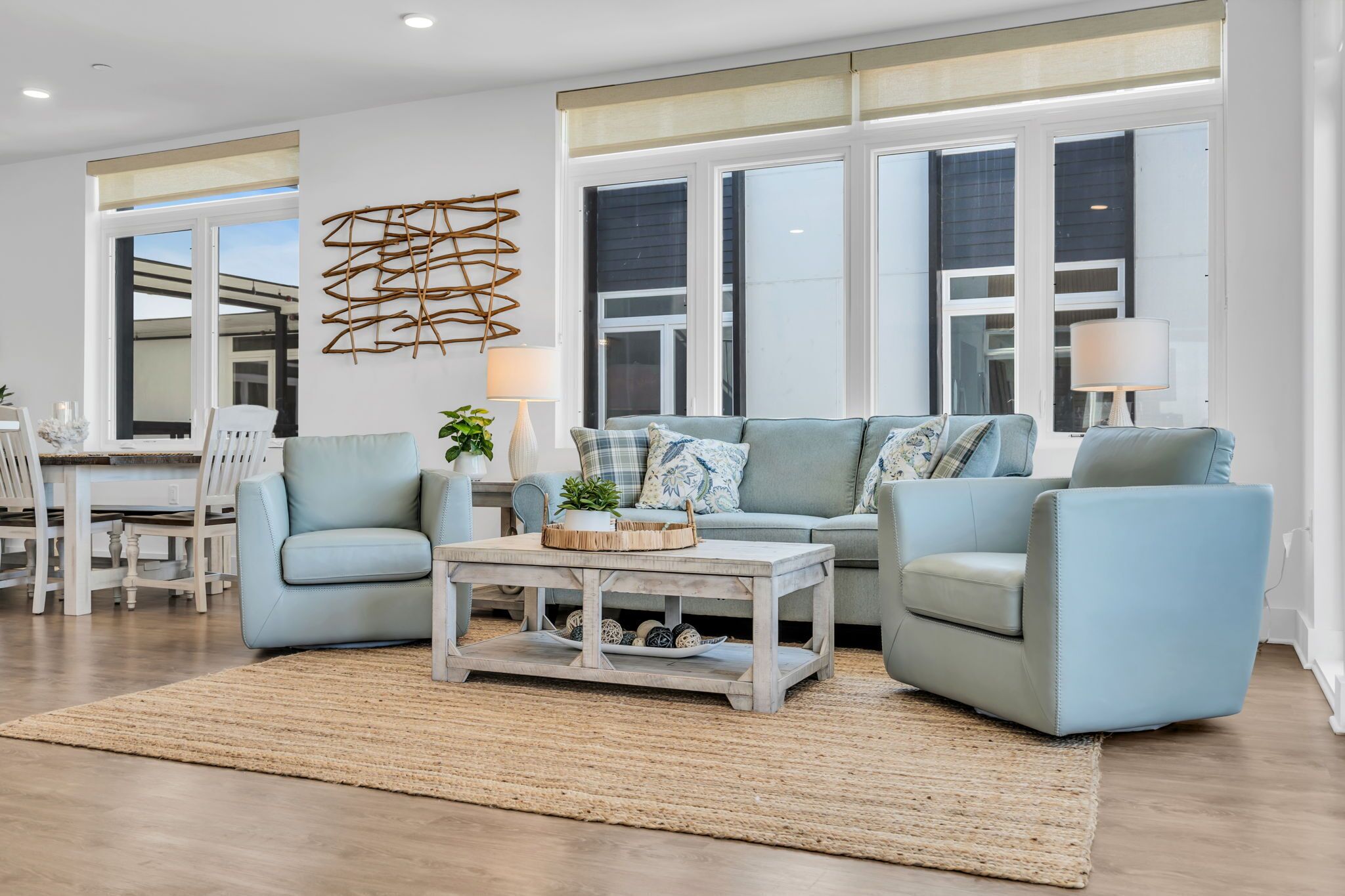 Una sala de estar moderna con un sofá azul claro, una mesa de centro y un comedor con una mesa y sillas blancas.
