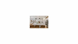 A modern kitchen with white cabinets, a central island, and pendant lighting. - Updated, Spacious TWHM - Close to Everything - Sleeps 8 - 5min to DFW airport (Irving)