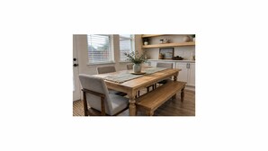 A dining area with a wooden table, chairs, and a bench. There is a potted plant on the table. - Updated, Spacious TWHM - Close to Everything - Sleeps 8 - 5min to DFW airport (Irving)