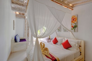 A bed with a canopy, a small table with a bottle, and a painting on the wall.