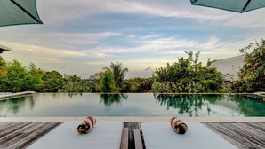 A poolside view with lounge chairs and umbrellas, surrounded by lush greenery and a clear sky. - Villa Olala Penida (Penida Island)