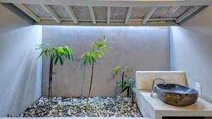 A bathroom with a stone sink, a bamboo plant, and a tiled floor. - Villa Olala Penida (Penida Island)