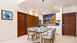 Ein moderner Essbereich mit einem Glastisch, weißen Stühlen und einer Chandelier.
