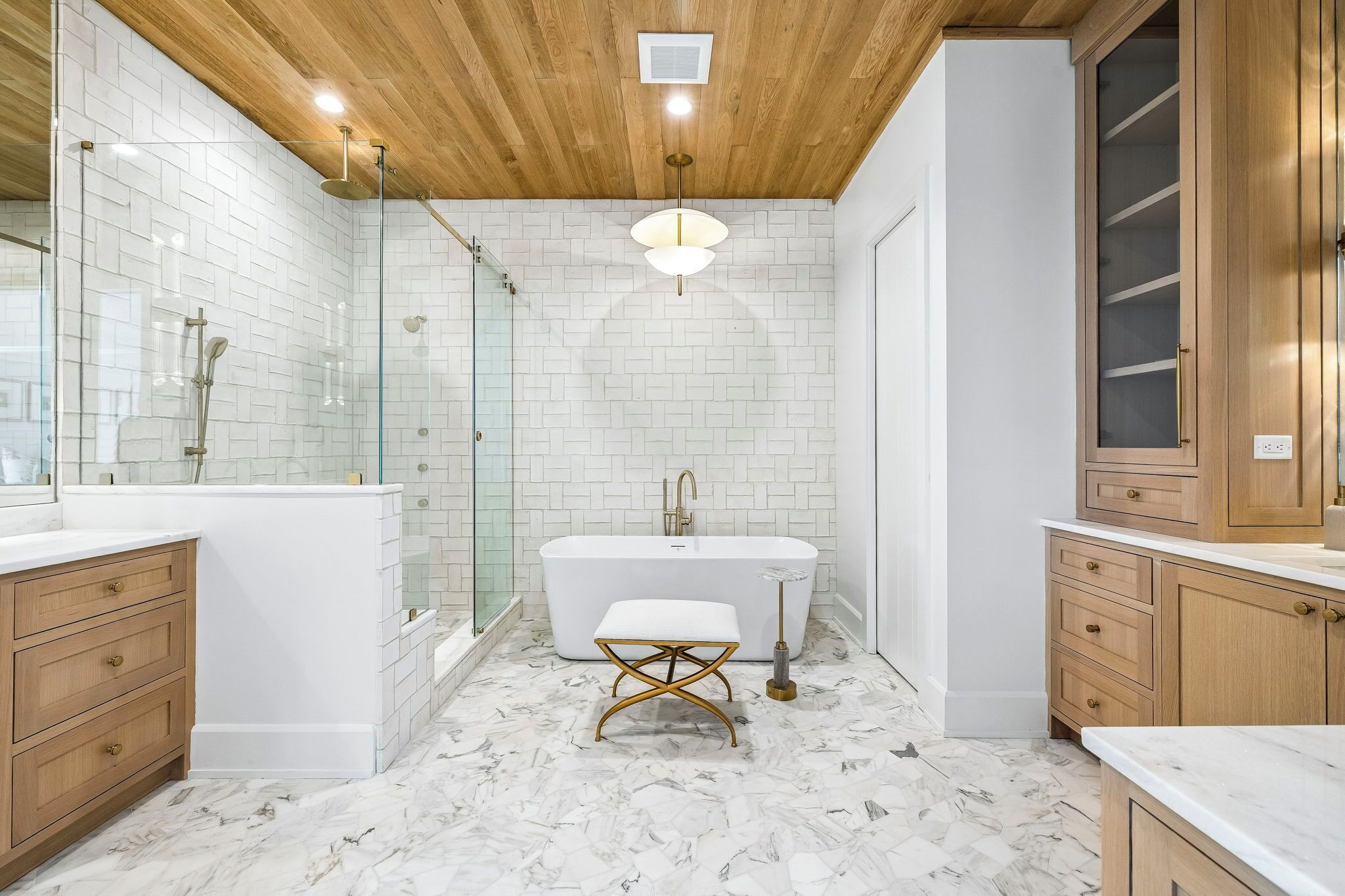 A modern bathroom with a freestanding bathtub, wooden cabinets, and a glass shower enclosure.
