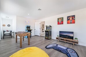Ein Wohnzimmer mit Tischfußball, Spielkonsole, Fernseher und einer Couch.