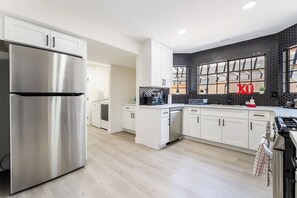 A modern kitchen with stainless steel appliances, white cabinetry, and a black tiled backsplash. - 4BR Oasis: Dual Suites & Pool | 10 Min Strip (Las Vegas)