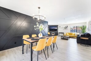A modern living room with a dining area, a flat-screen TV, and a fireplace. - 4BR Oasis: Dual Suites & Pool | 10 Min Strip (Las Vegas)