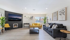 Un salon moderne avec une cheminée, un téléviseur et un canapé.