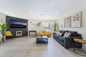 A modern living room with a fireplace, a TV, and a sofa. - 4BR Oasis: Dual Suites & Pool | 10 Min Strip (Las Vegas)