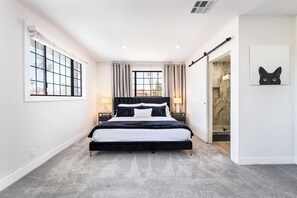 Ein modernes Schlafzimmer mit einem großen Bett, einem Nachttisch und einer Schiebetür zu einem Badezimmer.