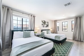 Habitación de hotel con dos camas, una ventana con cortinas, una obra de arte en la pared y una alfombra estampada.