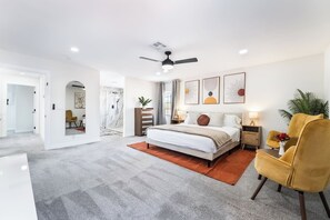A modern bedroom with a large bed, a ceiling fan, and artwork on the walls. - 4BR Oasis: Dual Suites & Pool | 10 Min Strip (Las Vegas)