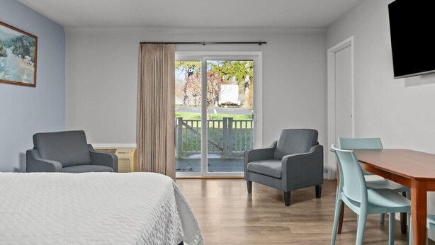 A hotel room with a bed, two armchairs, a dining table, and a TV.