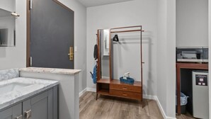 Une cuisine compacte équipée d’un four à micro-ondes encastré, d’un petit réfrigérateur et d’un meuble en bois.
